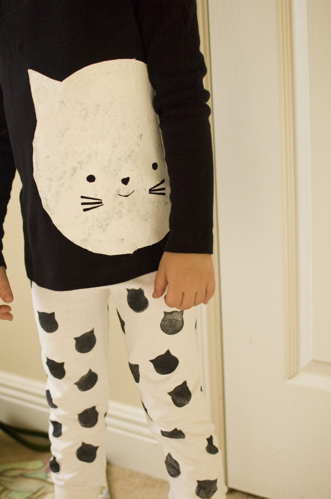 a kids pajama outfit with a cute cat stenciled on the top and small cat heads stamped onto the pants